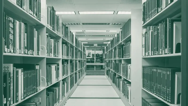 A library aisle, shelved books receding into the distance